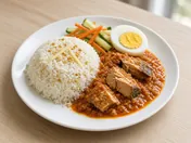 Nasi dagang: a mound of coconut rice with fenugreek seeds and ginger strips, chunks of tuna in thick red fish curry, half a boiled egg and cucumber and carrot pickle