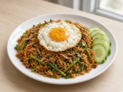 Nasi goreng kampung: spicy fried rice with crisp anchovies and water spinach on a white plate, topped with a fried egg, with cucumber slices