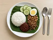 Nasi lemak on a banana leaf: coconut rice, sambal, fried anchovies, peanuts, cucumber and a boiled egg