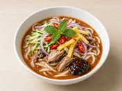 Bowl of Penang asam laksa: thick rice noodles in sour fish broth with cucumber, red onion, pineapple, mint, chilli and dark prawn paste