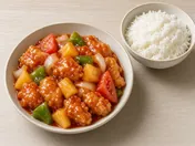 Sweet and sour chicken: crisp chicken pieces in glossy red sauce with pineapple, onion, green capsicum and tomato, with a bowl of rice